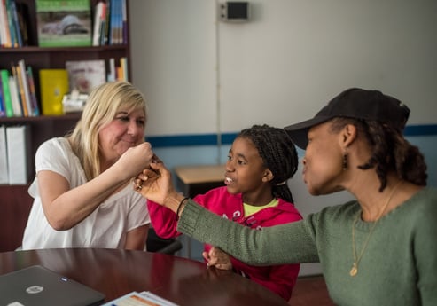 A parent, teacher, and student fistbump and smile. A parent, teacher, and student fistbump and smile.