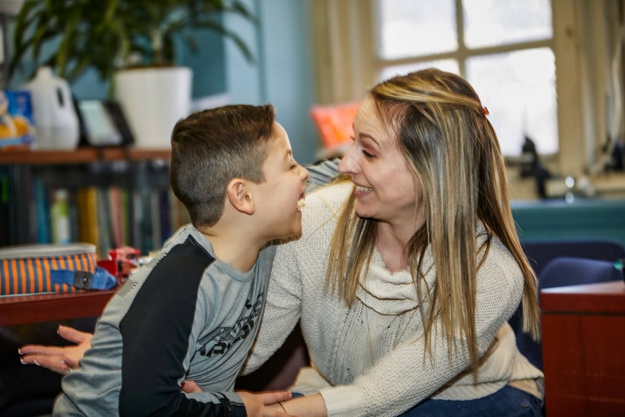 A boy and his family partner smile while partially embracing.