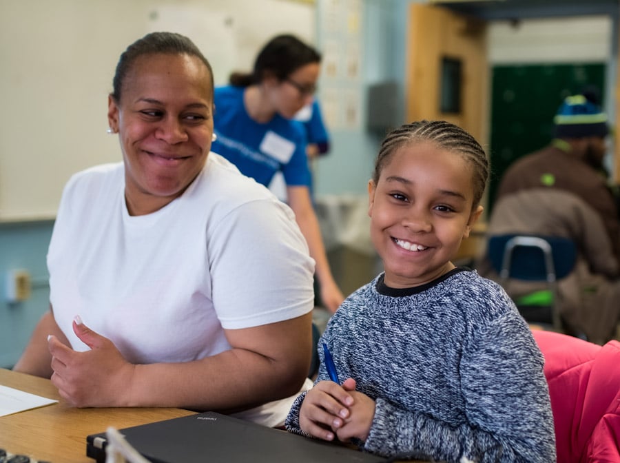 A girl and her family partner sit at a table and smile.