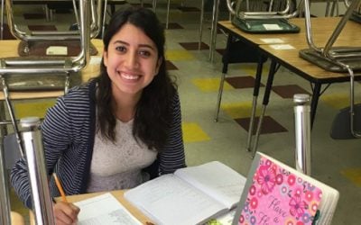 Ms. Salazar smiles while working at a desk. 